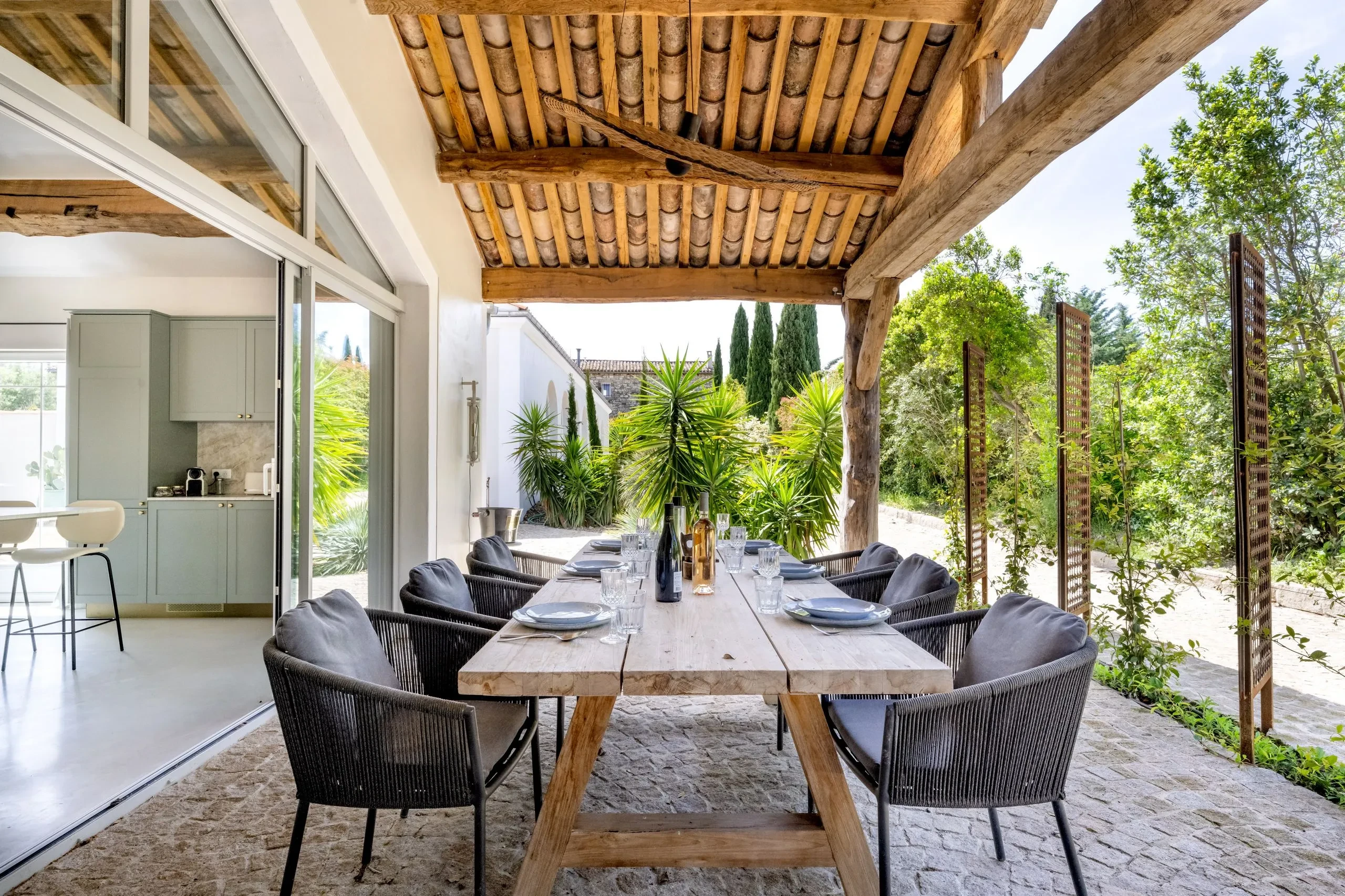 Terrasse ombragée avec table à manger en bois.