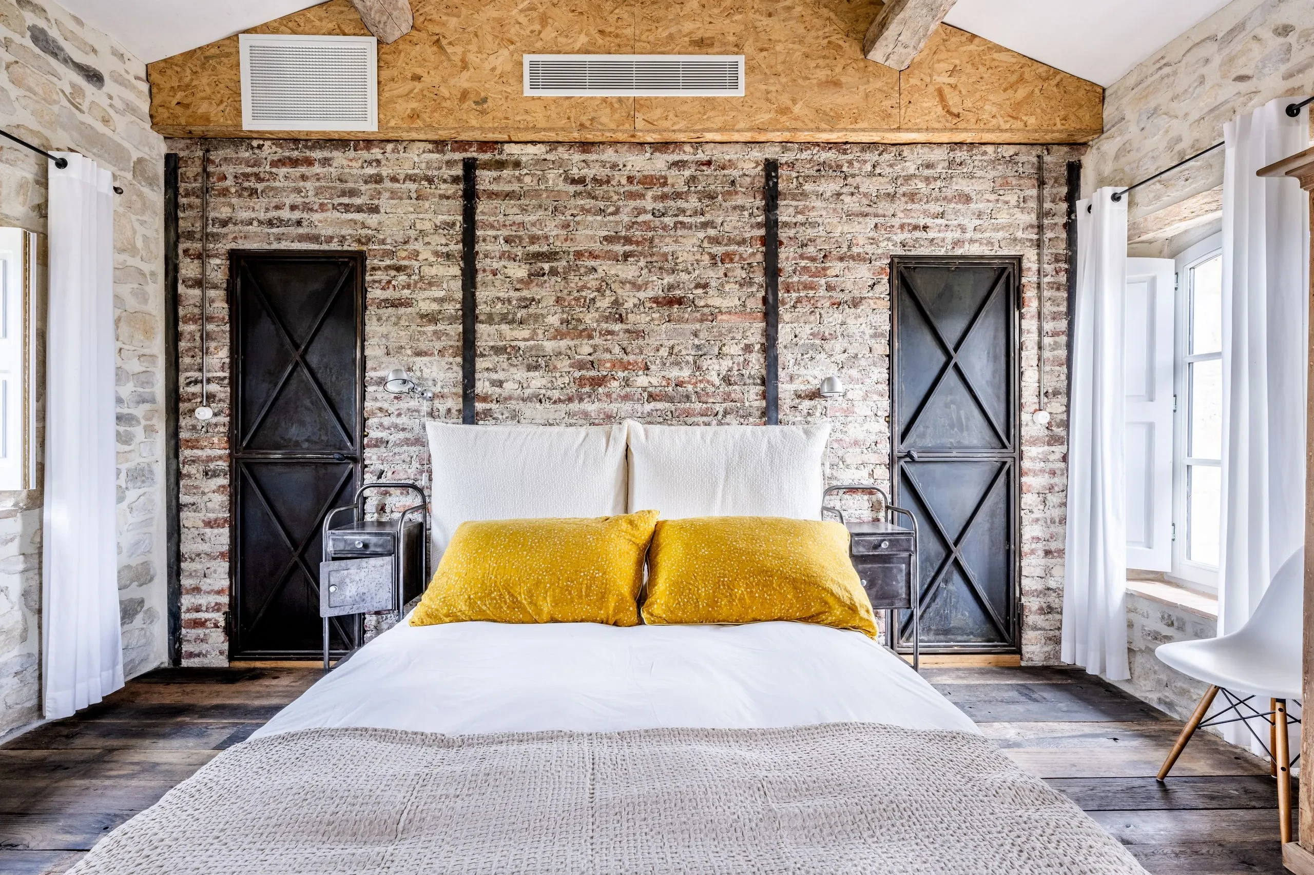 Chambre rustique avec mur en briques et coussins jaunes.