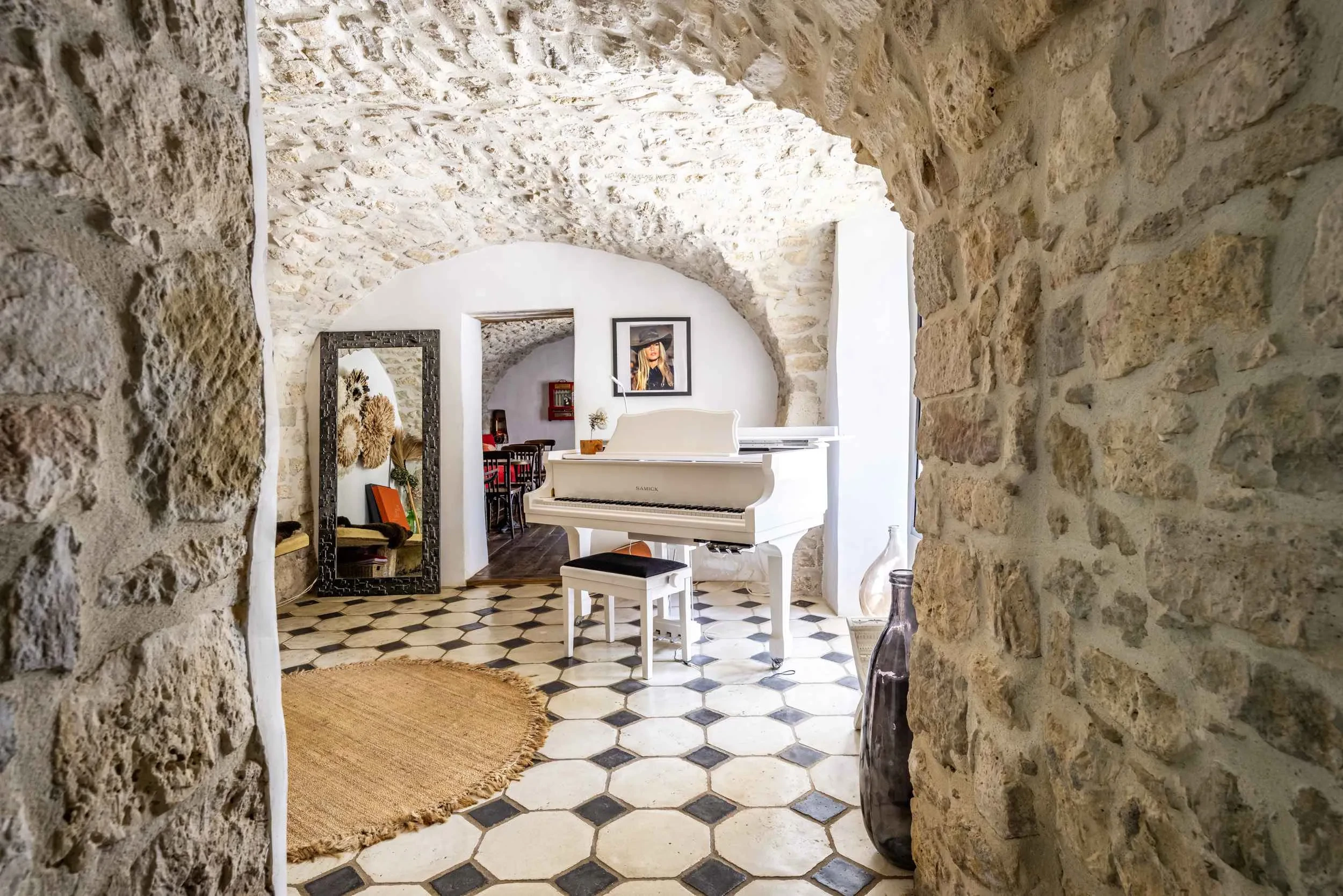 Intérieur en pierre avec piano blanc et miroir décoratif.