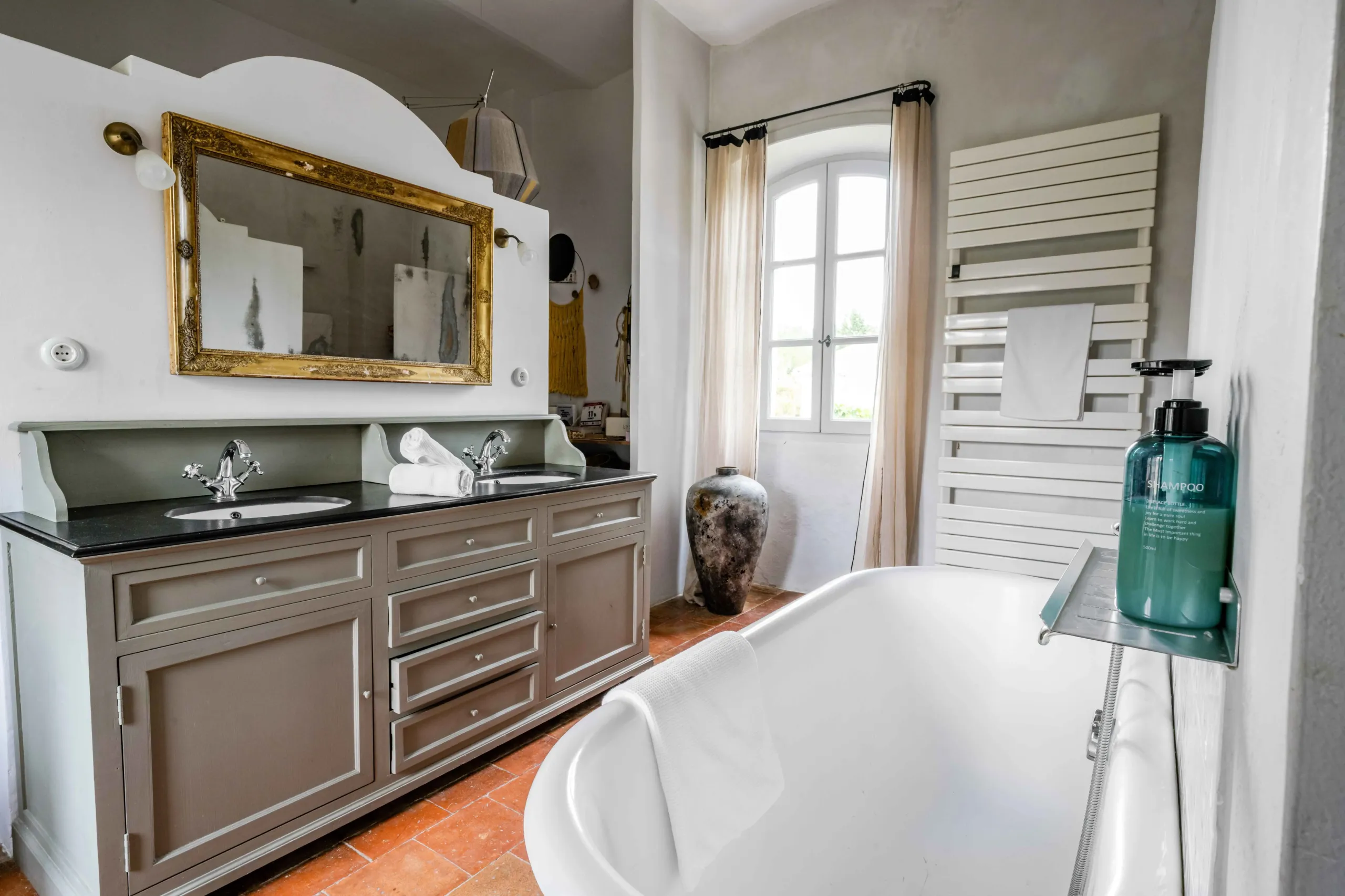 Salle de bain élégante avec baignoire et miroir doré.