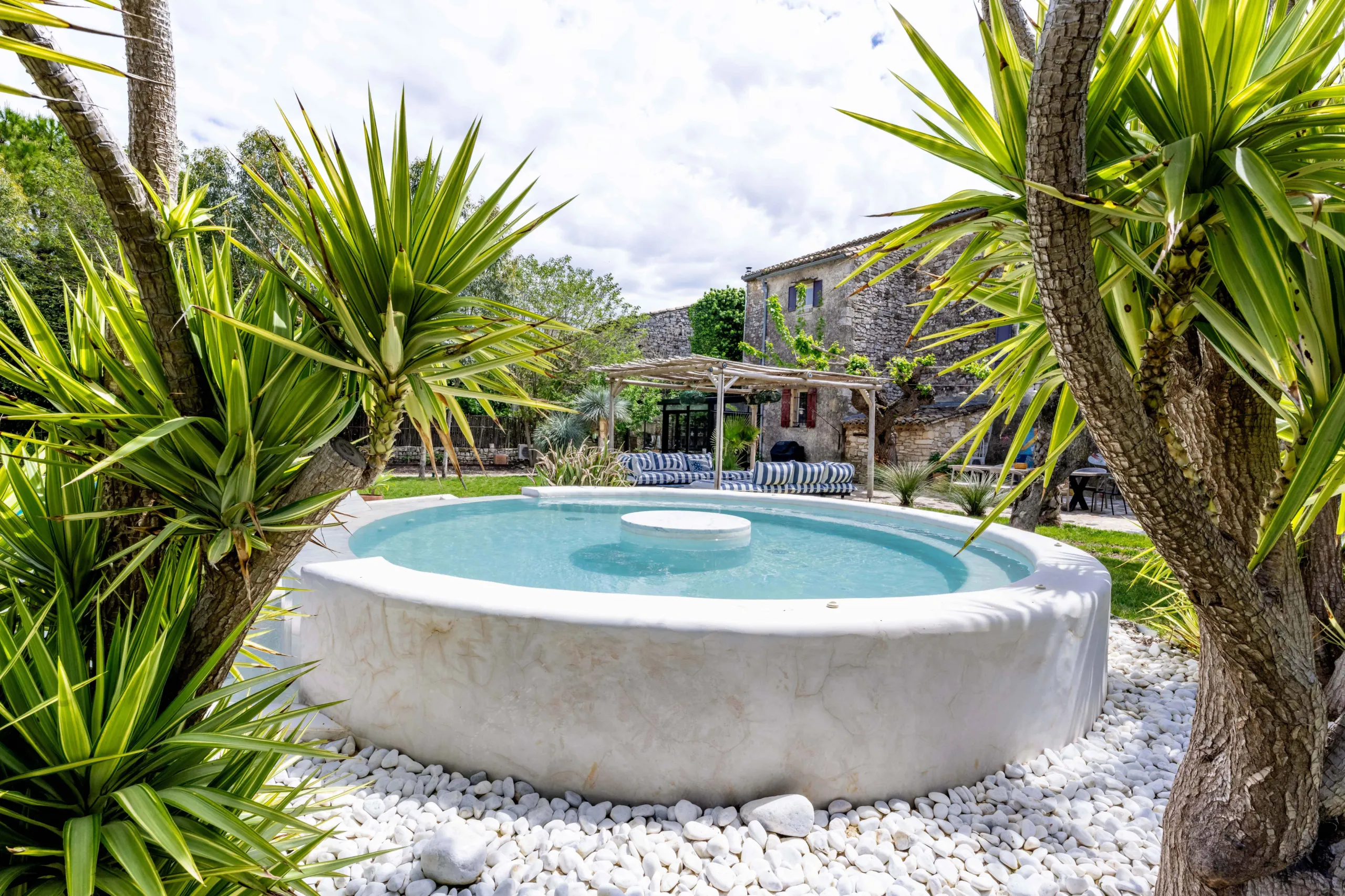 Jardin avec piscine ronde et verdure luxuriante.