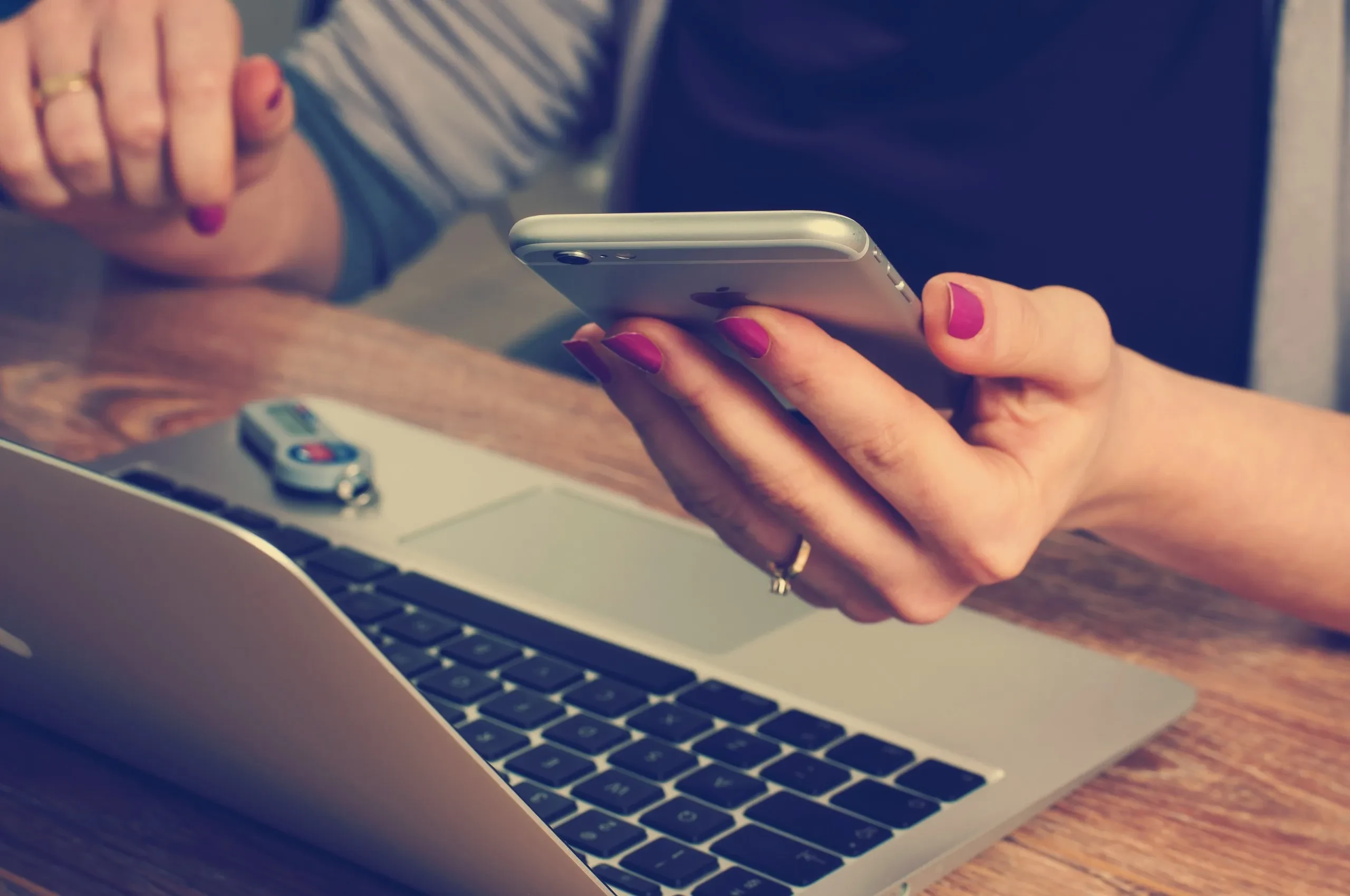 Personne utilisant un smartphone devant un ordinateur portable.