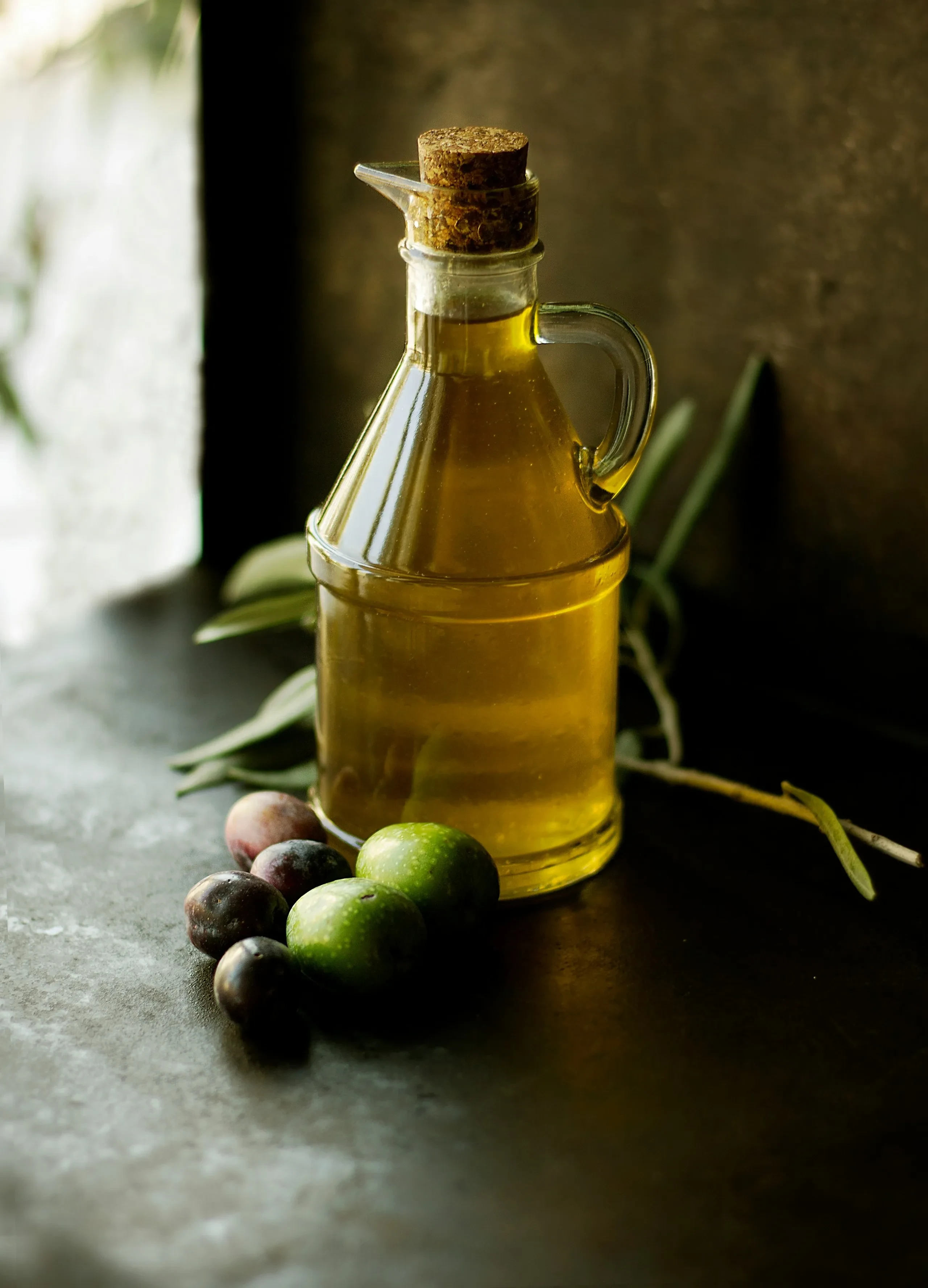 Bouteille d'huile d'olive avec des olives fraîches