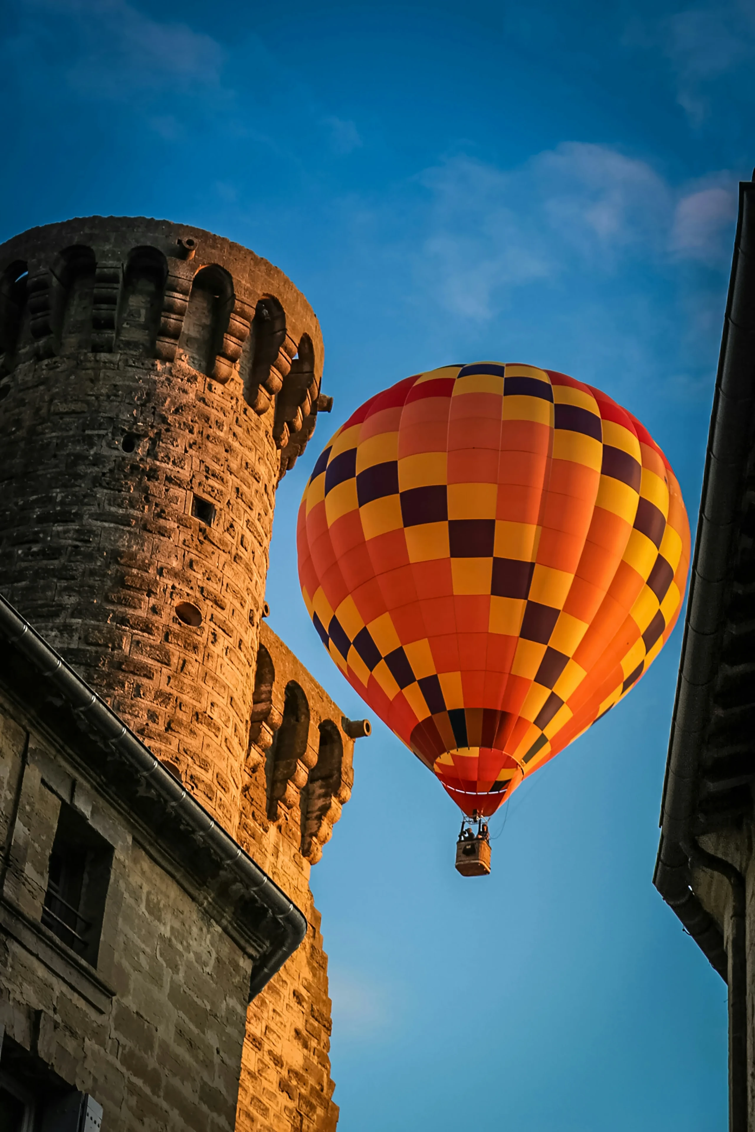 Montgolfière colorée près d'une tour médiévale au crépuscule.